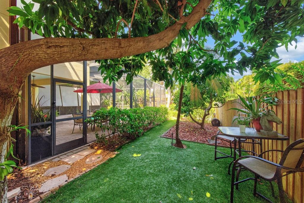 A backyard features a small artificial turf lawn, a patio table, and a screened-in pool area — 5916 S 6TH STREET, TAMPA, FL