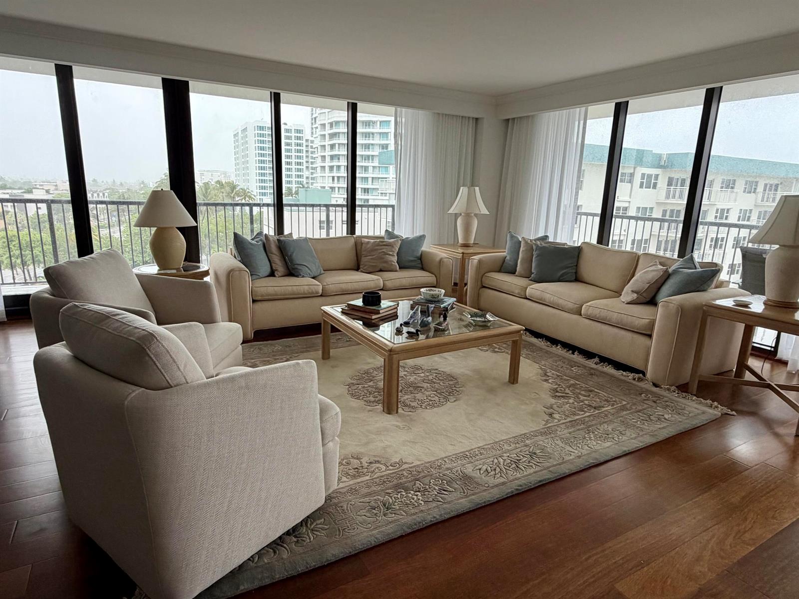 A living room with beige sofas, a glass-top coffee table, and floor-to-ceiling windows — 1800 S Ocean Boulevard Unit 612, Pompano Beach FL 33062, POMPANO BEACH, FL