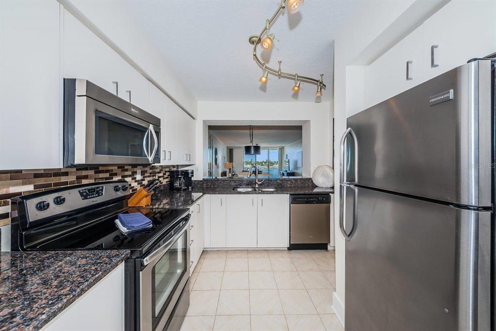 A kitchen with stainless steel appliances, white cabinets, granite countertops, and a tile floor — 6083 BAHIA DEL MAR CIRCLE UNIT 460, ST PETERSBURG, FL