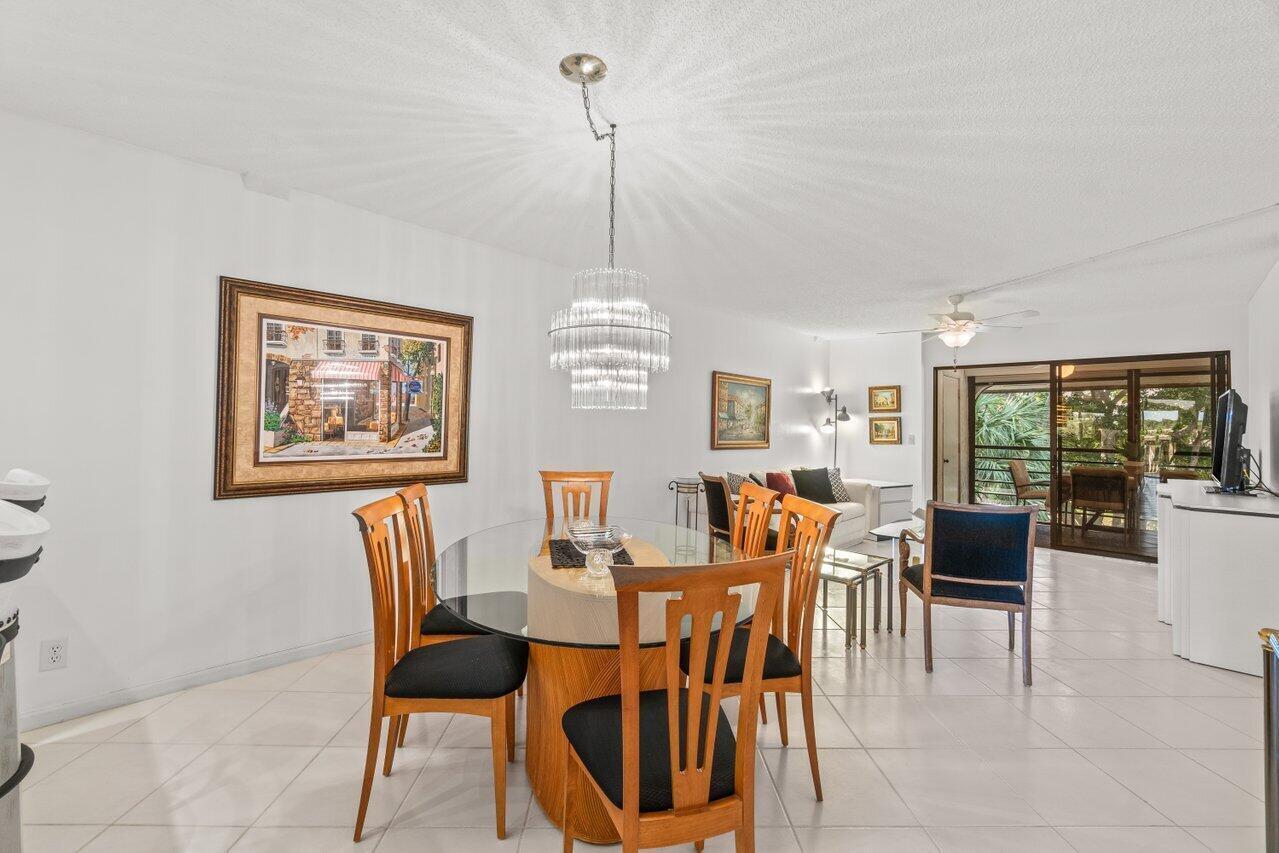 A dining area with a glass table and chandelier opens into a living room — 5380 Cedar Lake Drive # 303, Boynton Beach FL 33437, BOYNTON BEACH, FL
