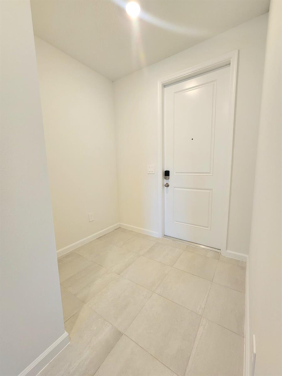 An entryway with light-colored tile flooring, white walls, and a white front door — 629 Salisbury Circle, Fort Pierce FL 34982, FORT PIERCE, FL