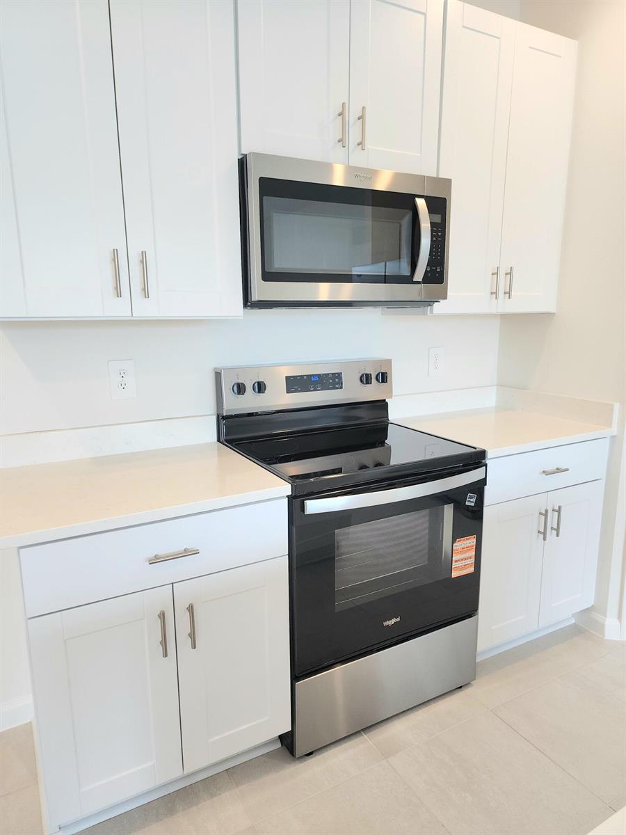 A kitchen features white cabinets, stainless steel appliances, and light-colored countertops — 629 Salisbury Circle, Fort Pierce FL 34982, FORT PIERCE, FL