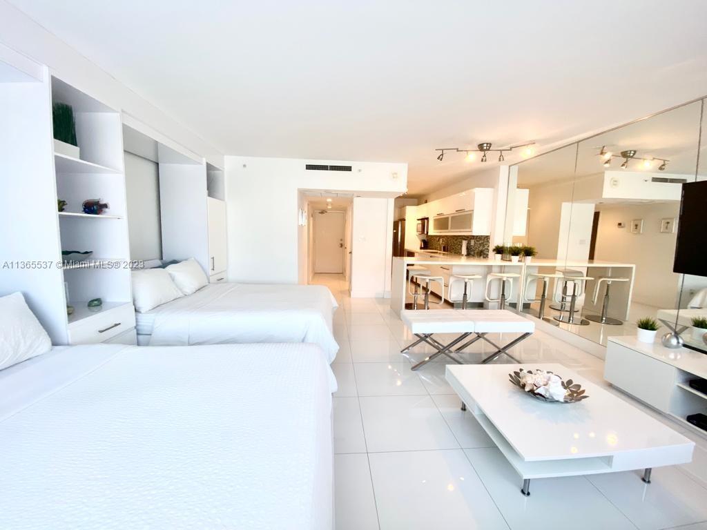 A studio apartment features two beds, a white kitchen, and a mirrored wall — 100 Lincoln Rd # 906, Miami Beach FL 33139, MIAMI BEACH, FL