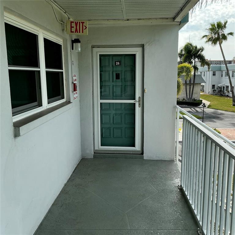 An exterior view of a balcony featuring a green door marked with the number 26 — 5267 81ST ST N UNIT 26, ST PETERSBURG, FL