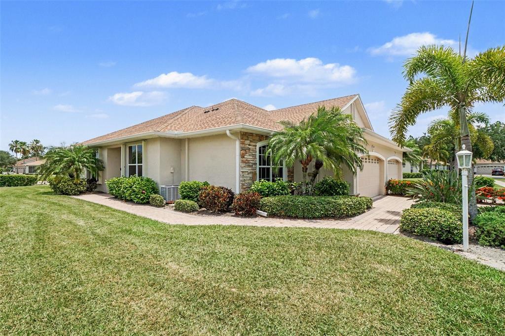 A single-story house with a tan stucco exterior, stone accents, and a paved driveway — 2593 COTTONWOOD LANE, NORTH PORT, FL