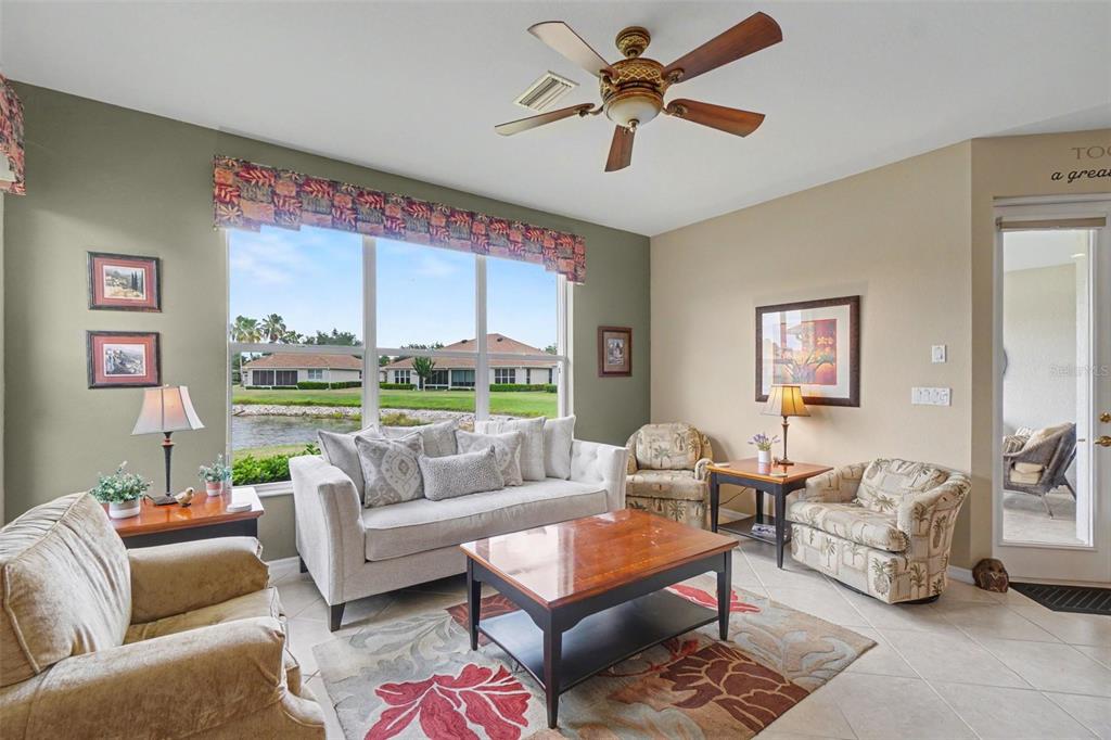 A living room with a sofa, armchairs, coffee table, ceiling fan, and a large window — 2593 COTTONWOOD LANE, NORTH PORT, FL