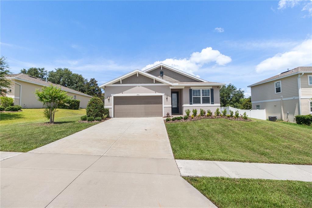 A single-story suburban house with a two-car garage and a concrete driveway — 2536 AUTUMN STREAM DRIVE, LEESBURG, FL
