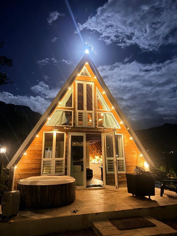 An A-frame cabin at night features a wooden exterior, large windows, and a patio hot tub — 717 CARR. 717, 4.2 INT, LOT 5, AIBONITO, PR