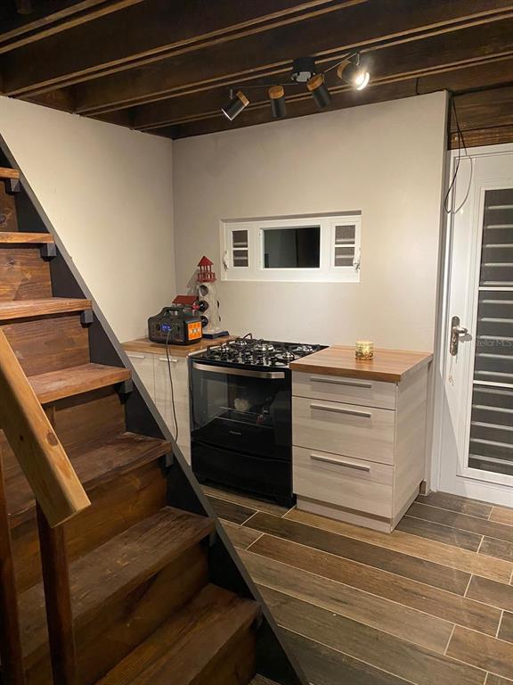 A kitchen area features a black stove, light wood cabinets, and a staircase — 717 CARR. 717, 4.2 INT, LOT 5, AIBONITO, PR