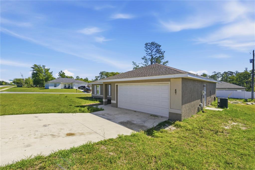 An exterior view of a single-story house with a two-car garage and concrete driveway — 407 MARION OAKS COURSE, OCALA, FL