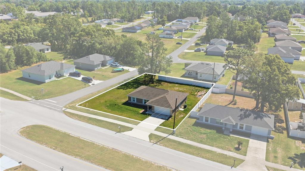 An aerial view shows a single-story house with a brown roof on a corner lot — 407 MARION OAKS COURSE, OCALA, FL