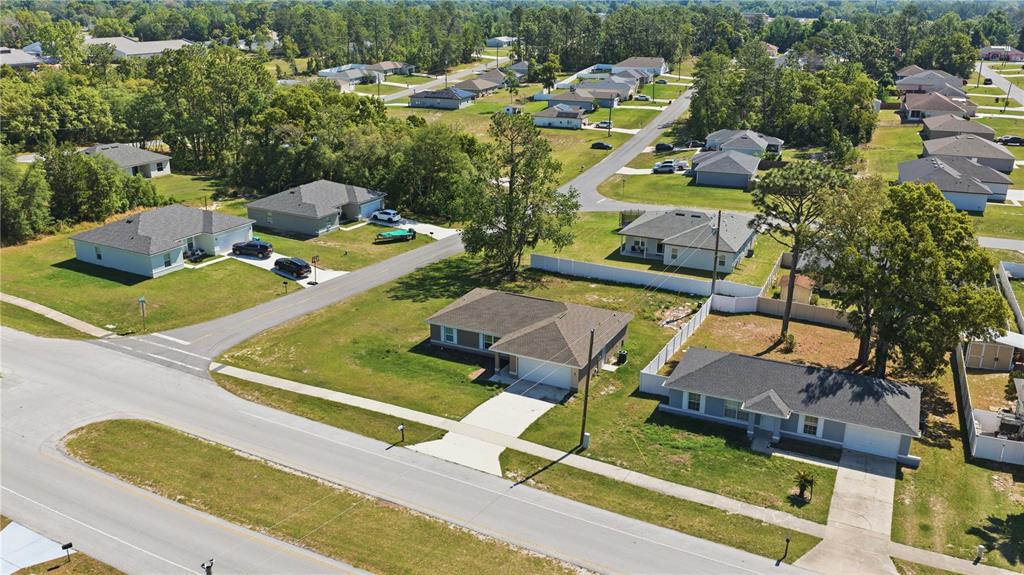 An aerial view shows several suburban single-family homes with driveways and lawns on a street — 407 MARION OAKS COURSE, OCALA, FL