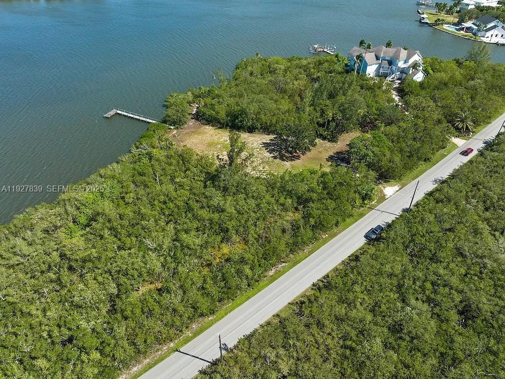 An aerial view shows a waterfront lot with a dock, dense vegetation, and a road — 250 Live Oak Dr, Vero Beach FL 32963, VERO BEACH, FL