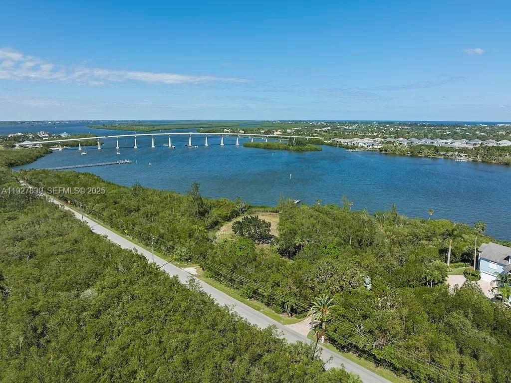 An aerial view shows a road running alongside dense vegetation, a waterway, and a bridge — 250 Live Oak Dr, Vero Beach FL 32963, VERO BEACH, FL