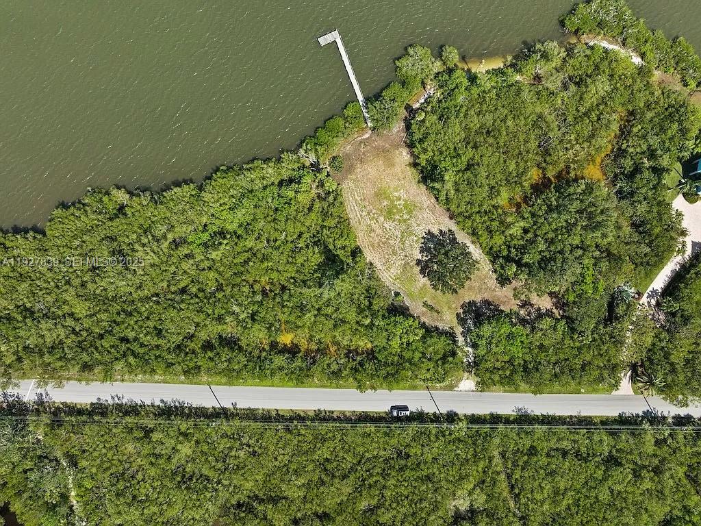 An aerial view shows a vacant waterfront lot with a private dock and dense vegetation — 250 Live Oak Dr, Vero Beach FL 32963, VERO BEACH, FL