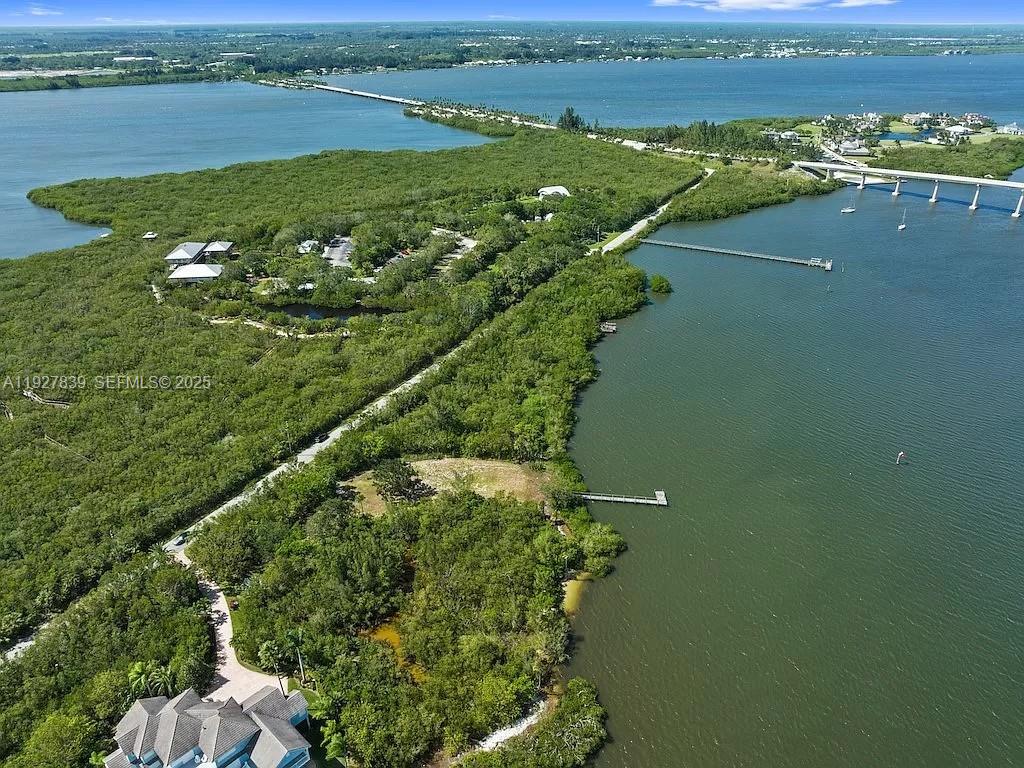 An aerial view shows a coastal property with dense vegetation, docks, and a nearby bridge — 250 Live Oak Dr, Vero Beach FL 32963, VERO BEACH, FL