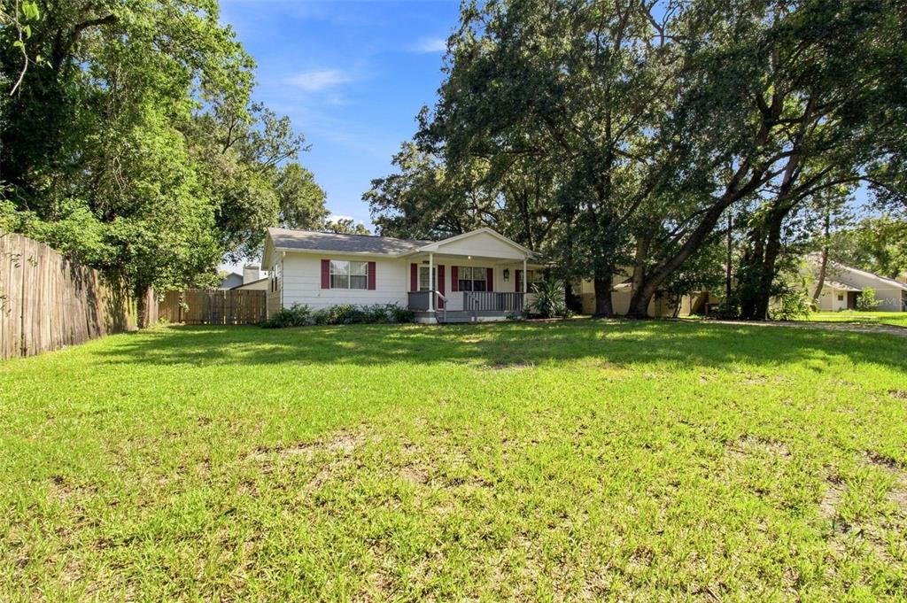 A single-story white house with a front porch sits behind a large grassy yard — 5206 PARADE STREET, TEMPLE TERRACE, FL