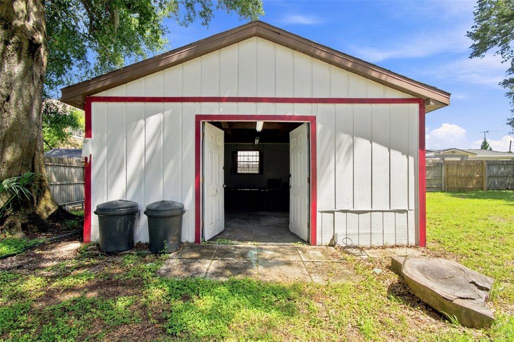 A detached white garage with red trim and open double doors sits in a yard — 5206 PARADE STREET, TEMPLE TERRACE, FL
