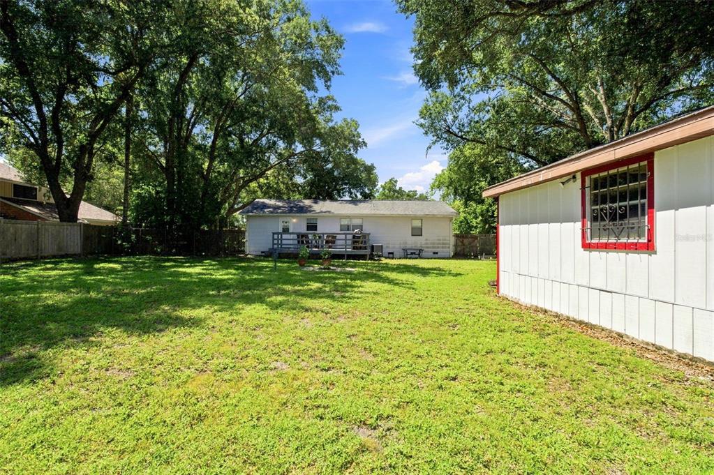 A rustic garage with exposed wooden walls, concrete flooring, built-in shelving, and an open door — 5206 PARADE STREET, TEMPLE TERRACE, FL