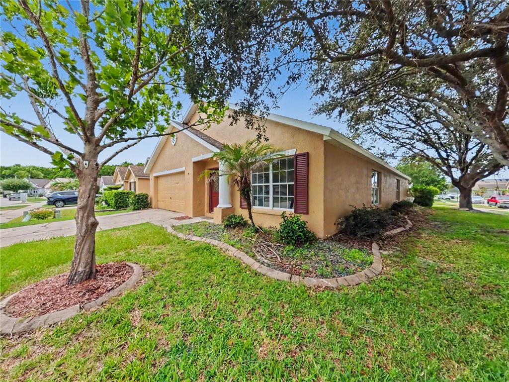 A tan stucco house with a two-car garage and a front yard with mature trees — 544 CYPRESS TREE COURT, ORLANDO, FL
