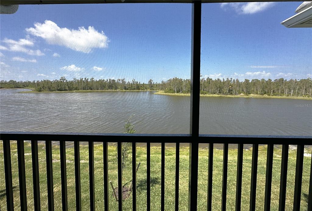 A view of a lake and grassy yard seen through a screened-in porch railing — 14241 HERITAGE LANDING BOULEVARD UNIT 1823, PUNTA GORDA, FL