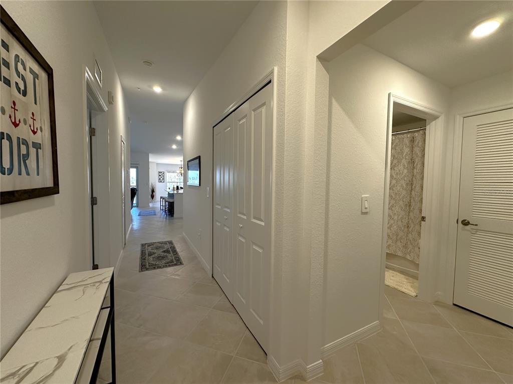 A hallway with tile flooring leads toward an open kitchen area with white doors — 14241 HERITAGE LANDING BOULEVARD UNIT 1823, PUNTA GORDA, FL