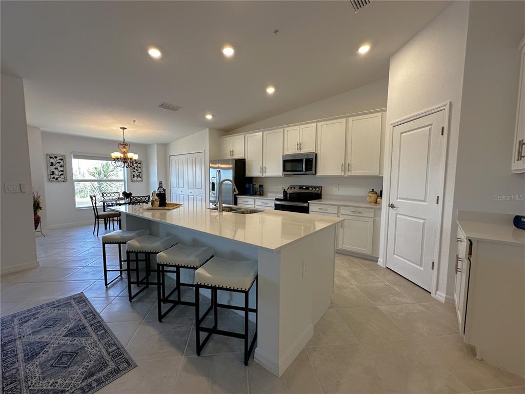 A kitchen features white cabinetry, a large quartz island with bar seating, and tile flooring — 14241 HERITAGE LANDING BOULEVARD UNIT 1823, PUNTA GORDA, FL