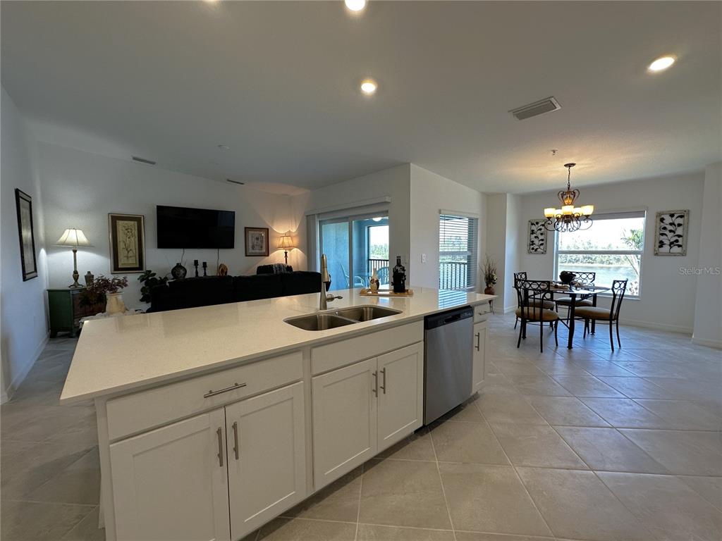 A kitchen island with a double sink faces a living area and a dining space — 14241 HERITAGE LANDING BOULEVARD UNIT 1823, PUNTA GORDA, FL