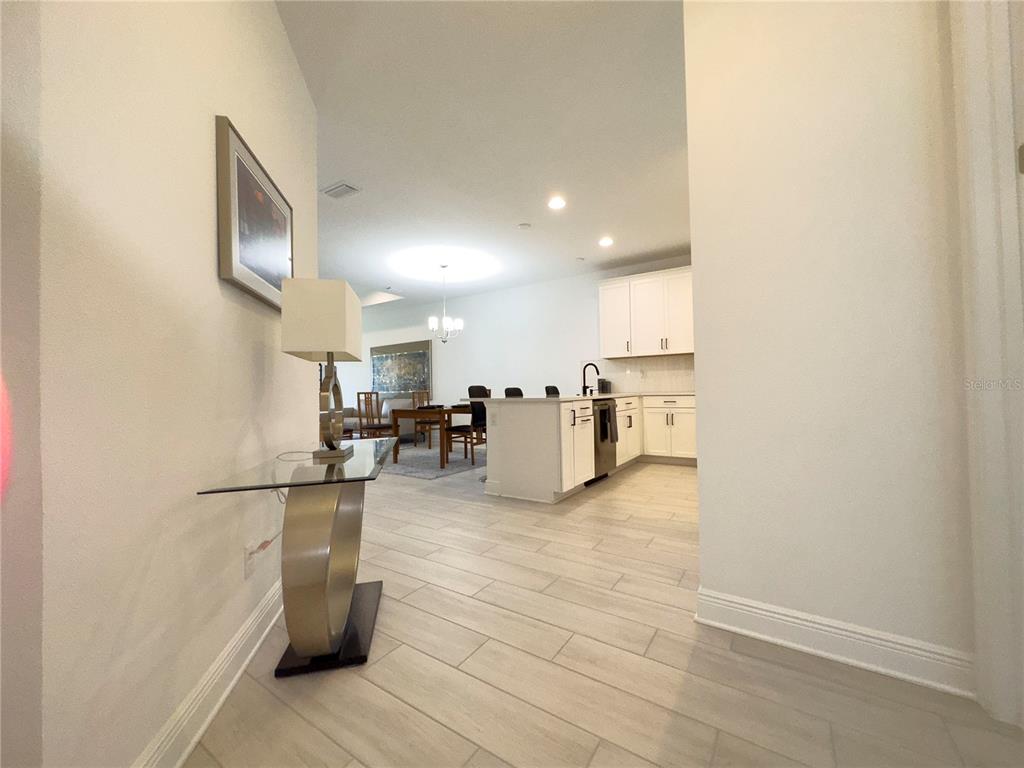 A view from a hallway into an open-concept kitchen and dining area with tile flooring — 17881 CHERISHED LOOP, BRADENTON, FL