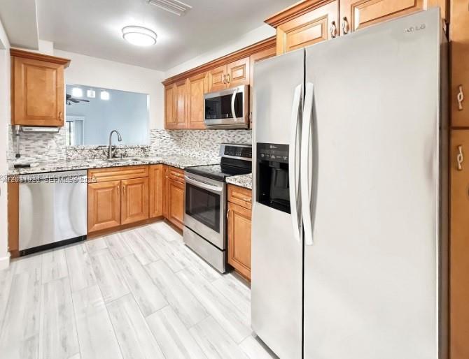 A kitchen features wood cabinets, stainless steel appliances, and light-colored wood-look flooring — 4182 S Pine Island Rd, Davie FL 33328, DAVIE, FL
