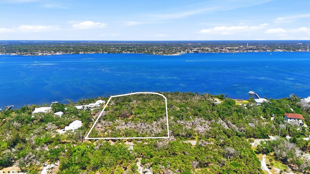 An aerial view shows a vacant, wooded waterfront lot outlined in white — 0 MANASOTA KEY ROAD, ENGLEWOOD, FL
