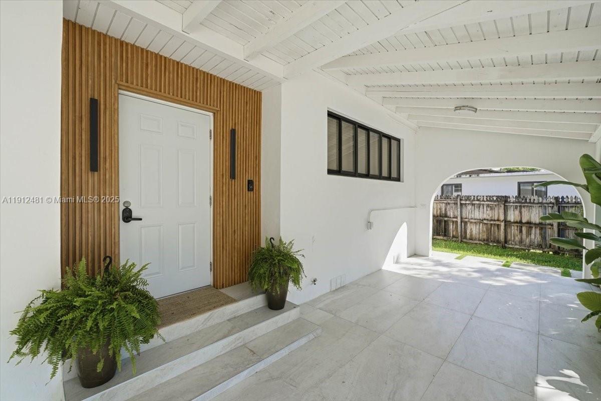 A white front door is framed by vertical wood slats on a covered porch — 10845 Peachtree Dr, Miami FL 33161, MIAMI, FL