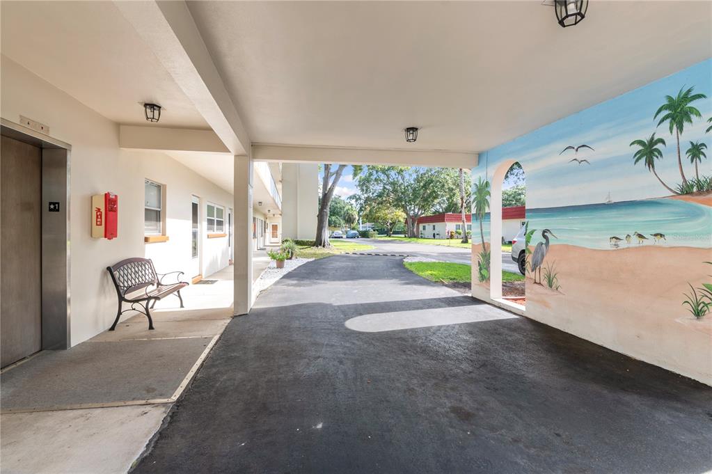 A covered parking area features a mural of a beach scene on the side wall — 5880 38TH AVENUE N UNIT 109, ST PETERSBURG, FL