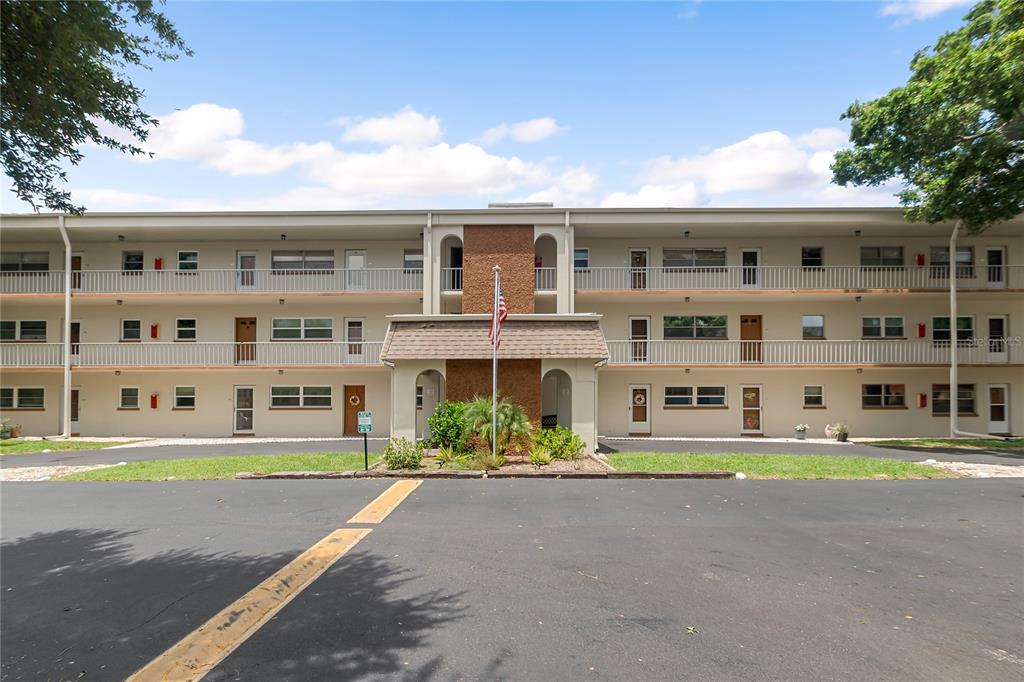 A three-story apartment building with a central brick entrance and a flag pole — 5880 38TH AVENUE N UNIT 109, ST PETERSBURG, FL