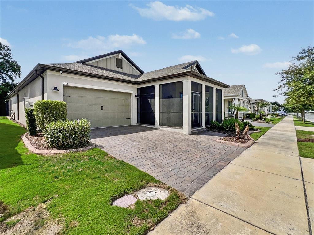 A single-story house with a paved driveway, a two-car garage, and a screened-in front porch — 2159 LIMESTONE TRAIL, KISSIMMEE, FL