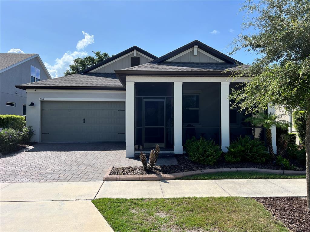 A single-story house with a paved driveway, a two-car garage, and a screened front porch — 2159 LIMESTONE TRAIL, KISSIMMEE, FL