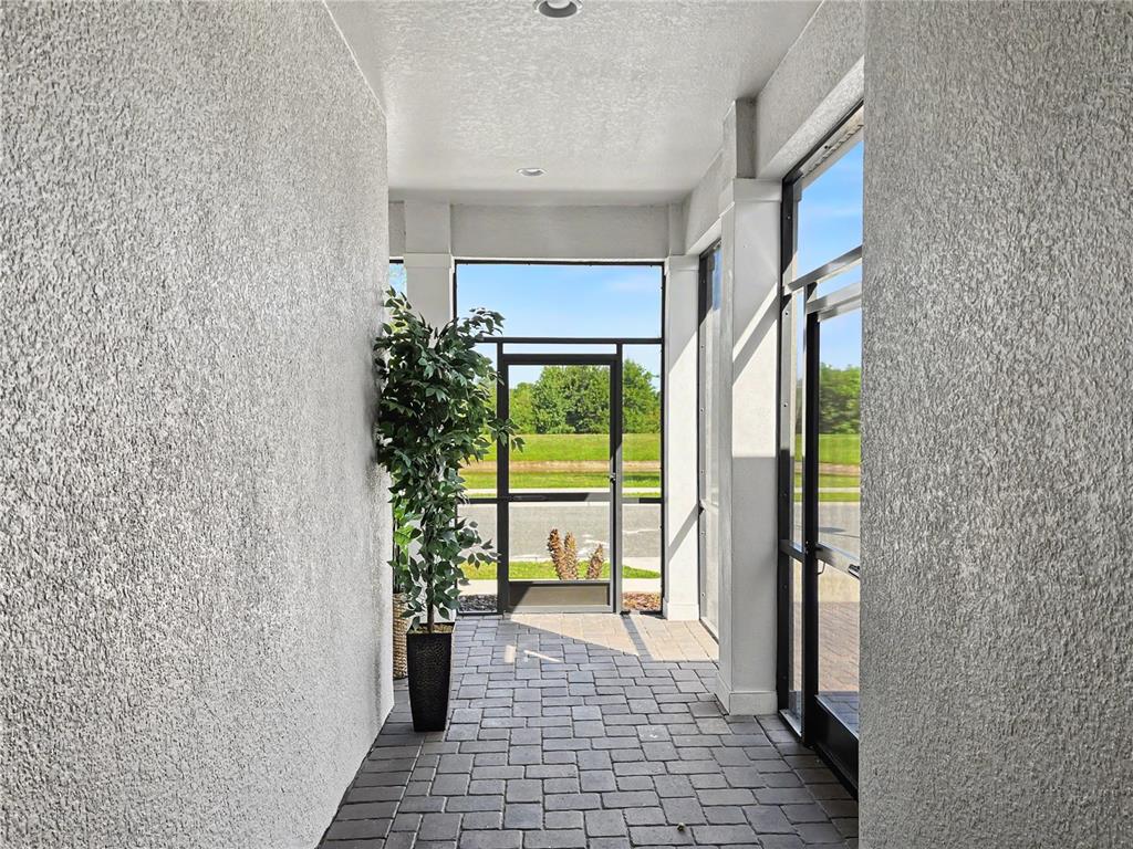 A covered entryway features a paver floor, textured walls, and a glass-paneled door — 2159 LIMESTONE TRAIL, KISSIMMEE, FL