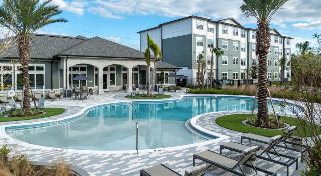 An outdoor swimming pool with lounge chairs sits in front of a multi-story apartment building — 10881 CALADESI AVENUE UNIT B2, TAMPA, FL