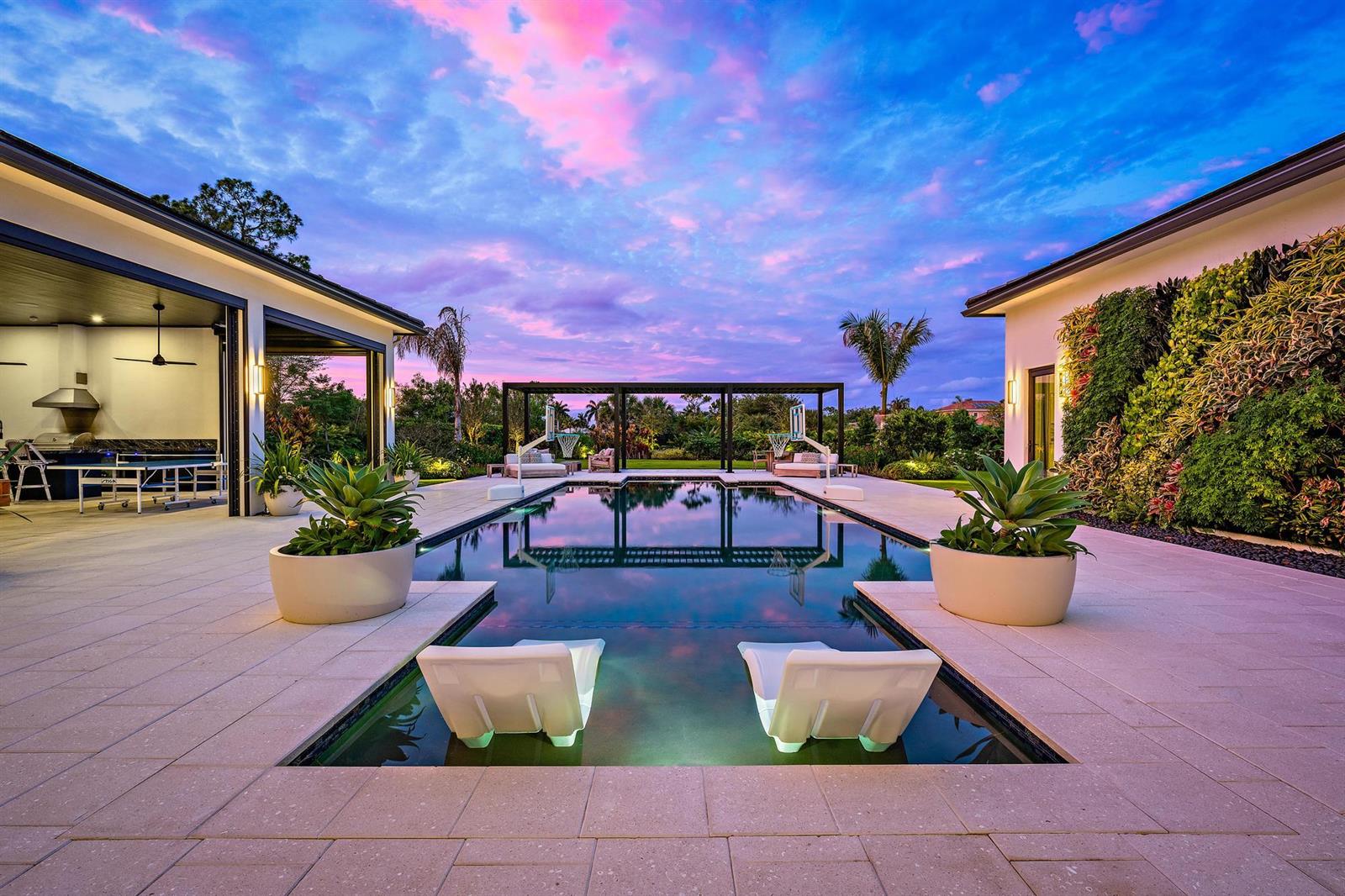 A modern backyard features a swimming pool with lounge chairs, a pergola, and outdoor seating — 6634 Audubon Trace W, West Palm Beach FL 33412, WEST PALM BEACH, FL