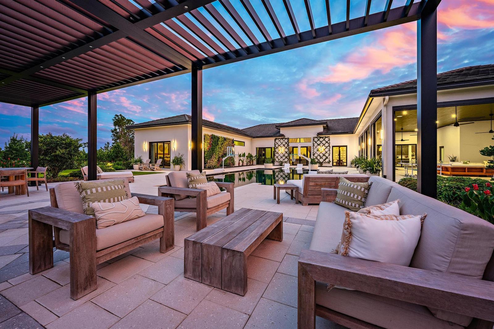 A modern outdoor patio features a pergola, lounge furniture, and a swimming pool at sunset — 6634 Audubon Trace W, West Palm Beach FL 33412, WEST PALM BEACH, FL