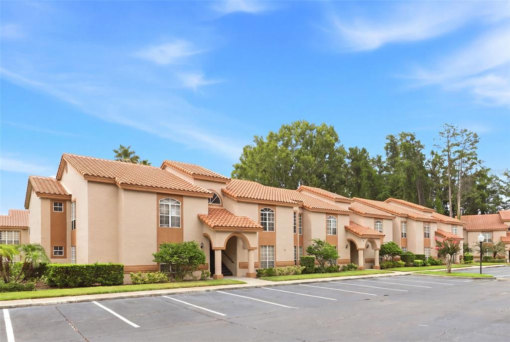 A multi-story apartment building with a tan stucco exterior and a terracotta tile roof — 4696 SUSSEX TERRACE UNIT 202, ORLANDO, FL