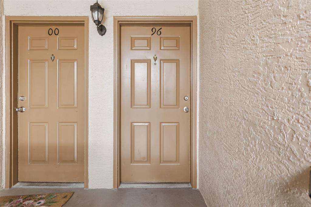 Two tan apartment doors with numbers 00 and 96 are set in a textured wall — 4696 SUSSEX TERRACE UNIT 202, ORLANDO, FL