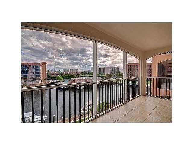 A screened-in balcony with tile flooring overlooks a canal, boats, and surrounding apartment buildings — 2871 N Ocean Boulevard N # V345, Boca Raton FL 33431, BOCA RATON, FL