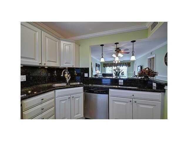 A kitchen with white cabinets, dark granite countertops, and a pass-through window to the living area — 2871 N Ocean Boulevard N # V345, Boca Raton FL 33431, BOCA RATON, FL