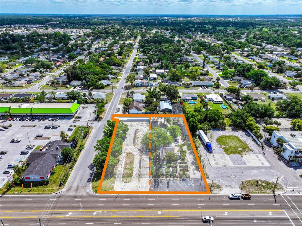 An aerial view shows two adjacent commercial lots with paved surfaces and trees along a road — 6605 14TH STREET W, BRADENTON, FL