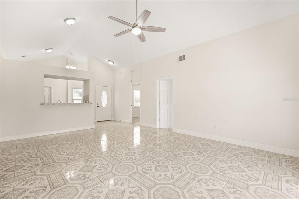 A bright, open-concept living area features vaulted ceilings, a ceiling fan, and patterned tile flooring — 948 OCALA WOODS LANE, ORLANDO, FL