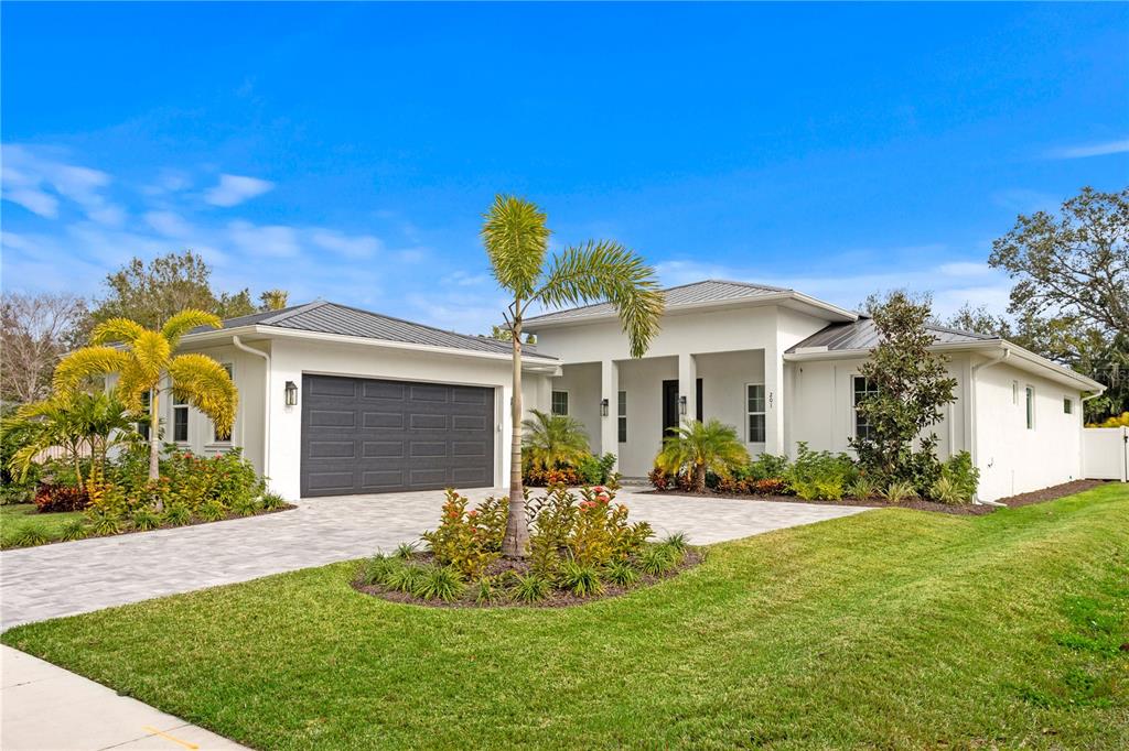 A single-story house with a dark metal roof, white exterior, and a paved driveway — 201 S SHADE AVENUE, SARASOTA, FL