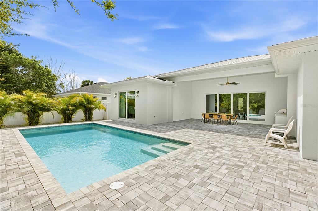 A backyard patio features a swimming pool, outdoor dining set, and white exterior walls — 201 S SHADE AVENUE, SARASOTA, FL