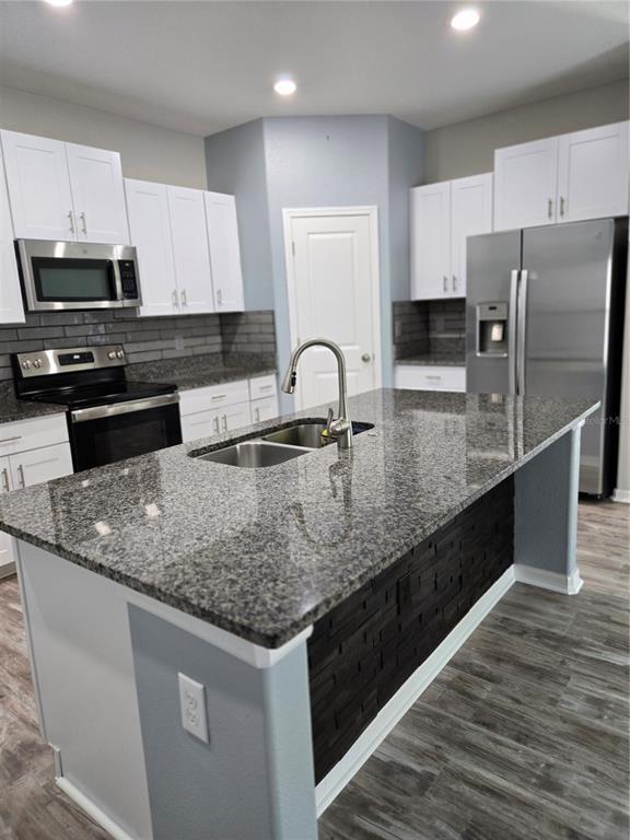 A kitchen features white cabinets, granite countertops, a central island, and stainless steel appliances — 1677 BLUE ROSE DRIVE, RUSKIN, FL