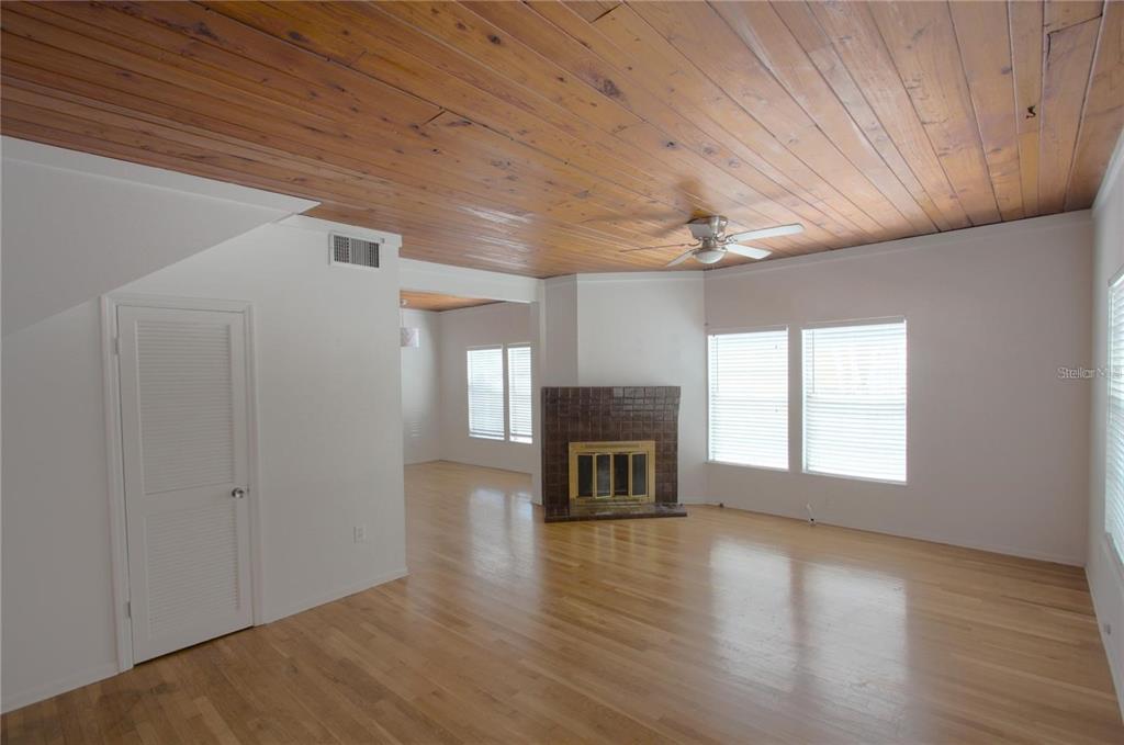 A living room features light hardwood floors, a wood-paneled ceiling, and a brown tiled fireplace — 303 S OSPREY AVENUE UNIT 303, SARASOTA, FL